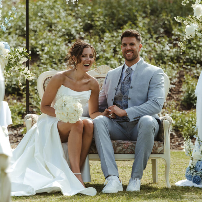 Brautpaar sitzt gemeinsam bei einer eleganten Hochzeit im Grünen