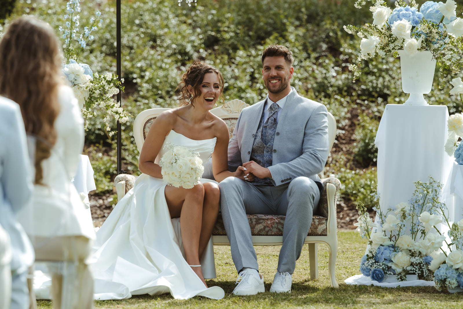 Brautpaar sitzt gemeinsam bei einer eleganten Hochzeit im Grünen